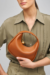 Profile view of model wearing the Oroton Clara Smooth Mini Bag in Amber and Smooth Leather Exterior for Women