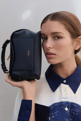 Profile view of model wearing the Oroton Mica Mini Bowler in North Sea and Pebble leather for Women