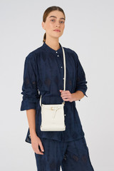 Profile view of model wearing the Oroton Margot Tiny Bucket Bag in Clotted Cream and Pebble leather for Women