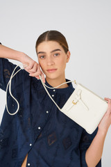 Profile view of model wearing the Oroton Margot Tiny Bucket Bag in Clotted Cream and Pebble leather for Women