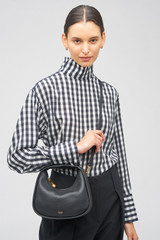 Profile view of model wearing the Oroton Clara Mini Bag in Black and Pebble leather for Women