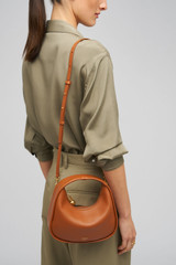 Profile view of model wearing the Oroton Clara Smooth Mini Bag in Amber and Smooth Leather Exterior for Women