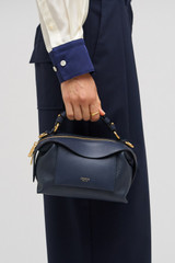 Profile view of model wearing the Oroton Mica Mini Bowler in North Sea and Pebble leather for Women