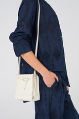 Profile view of model wearing the Oroton Margot Tiny Bucket Bag in Clotted Cream and Pebble leather for Women