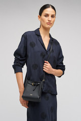Profile view of model wearing the Oroton Margot Tiny Bucket Bag in Black and Pebble leather for Women